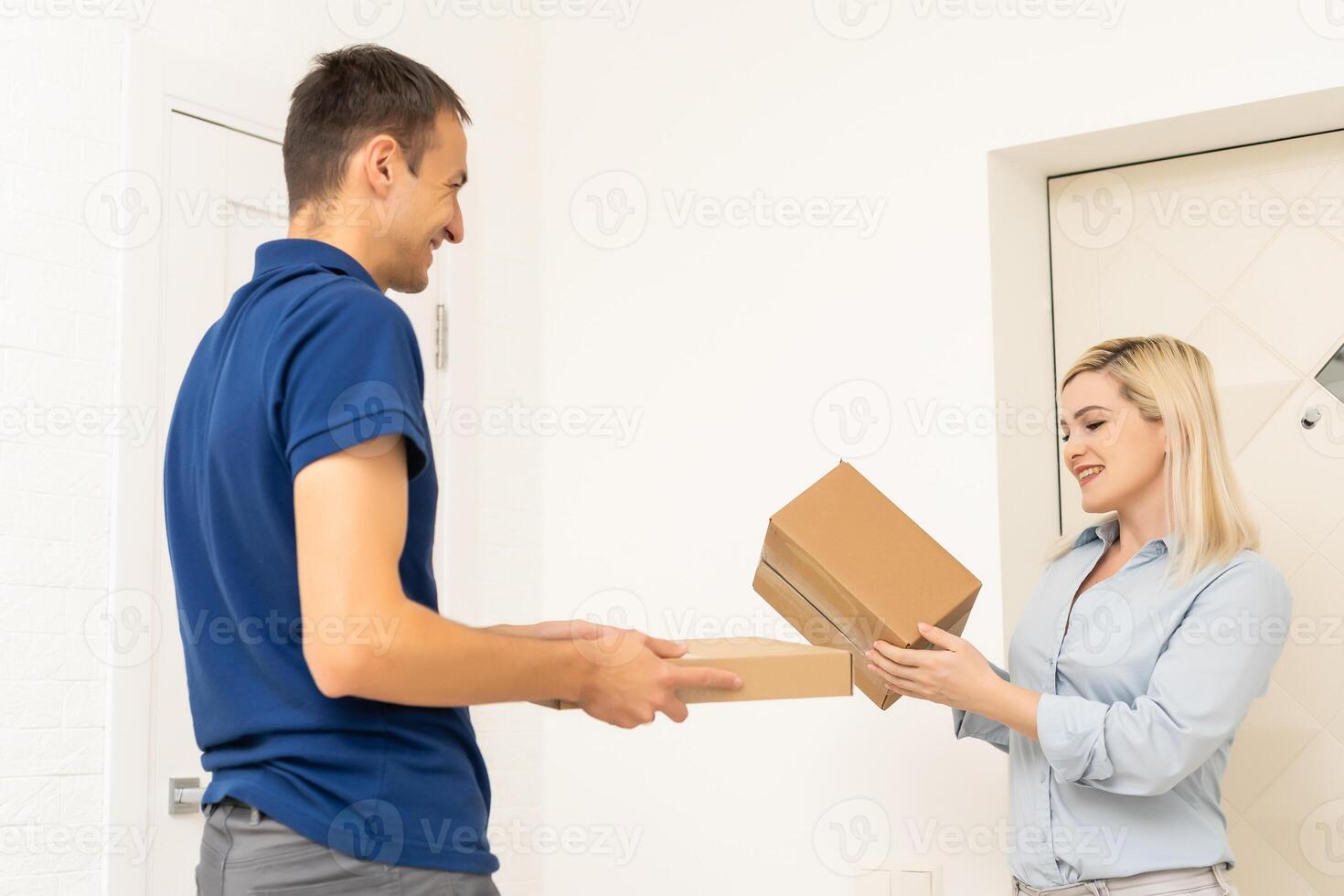 woman receiving boxes from postman at the door in home delivery concept. Woman received the parcel from the postman at home. Postman giving cardboard box to young woman. photo