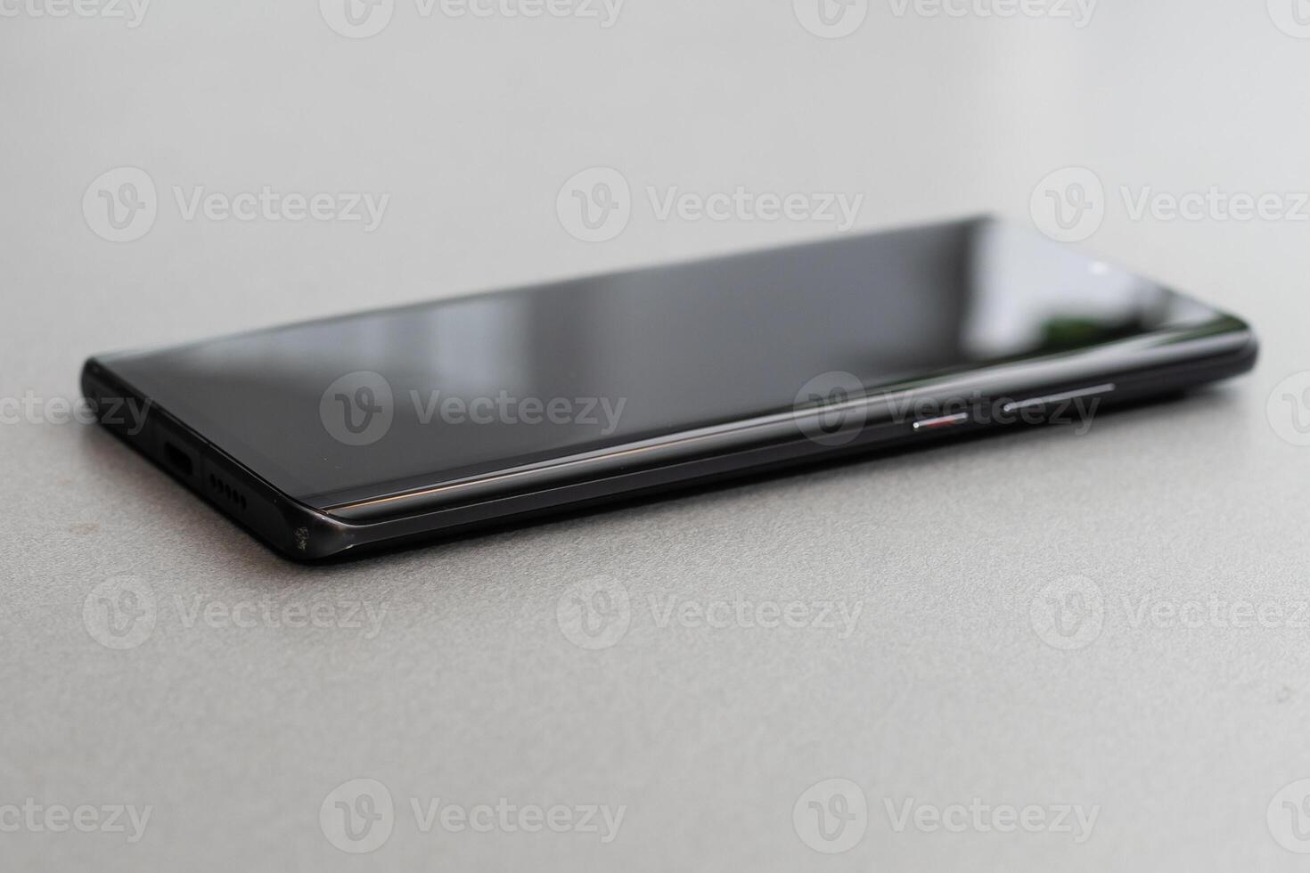 Black modern mobile phone with blank screen on black stone table background. Smartphone on old dark grey vintage texture background. photo