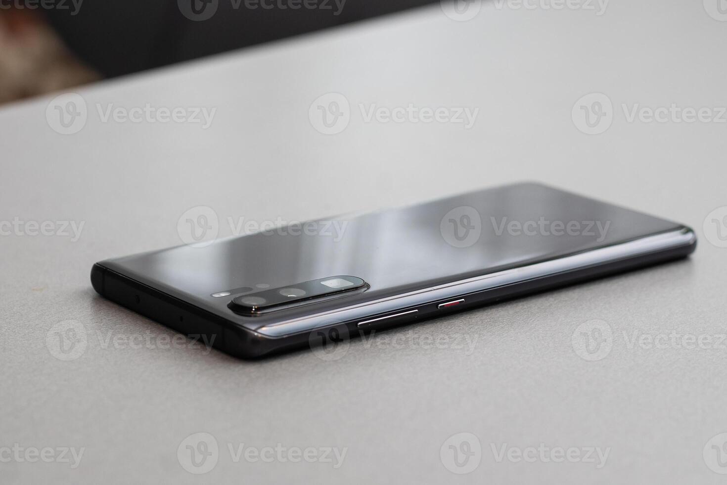 Black modern mobile phone with blank screen on black stone table background. Smartphone on old dark grey vintage texture background. photo