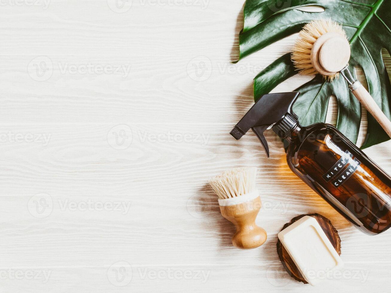 Zero waste home cleaning concept. Amber bottle with washing solution, brush and soap on white wood table. photo