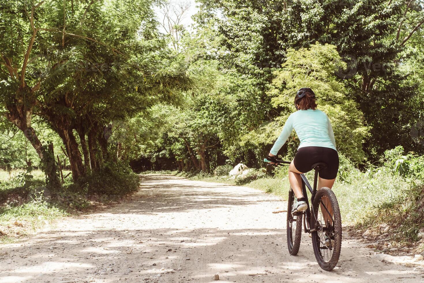 unrecognizable woman in sportswear for cyclists riding a bicycle running on a dirt road. sport life, wellness and adventure concept. copy space. photo