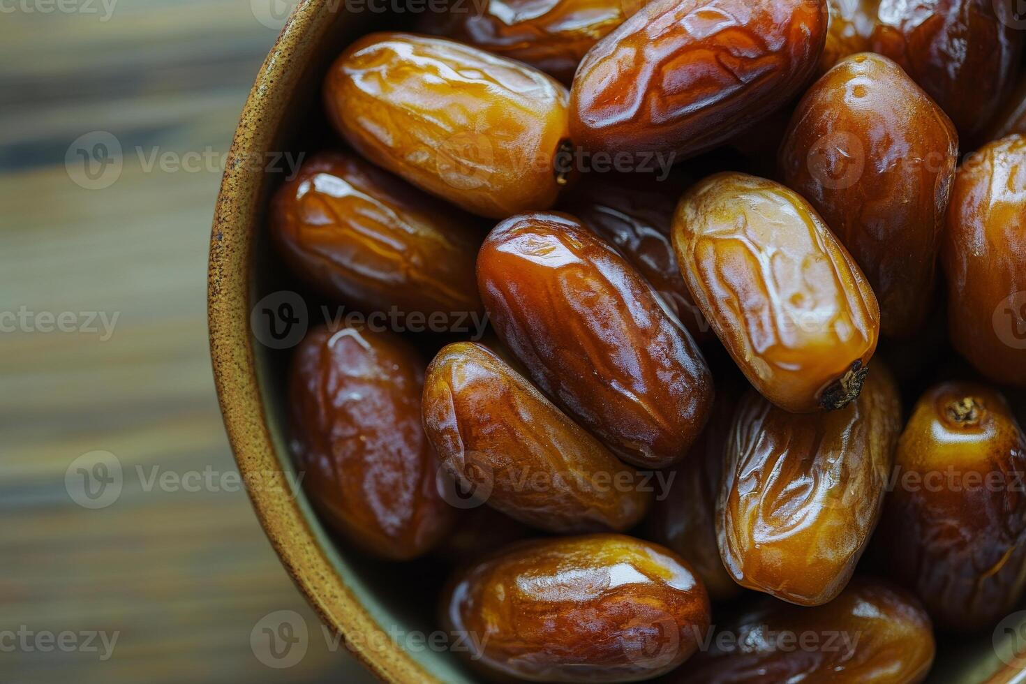 A bowl of dates sitting on a wooden table photo
