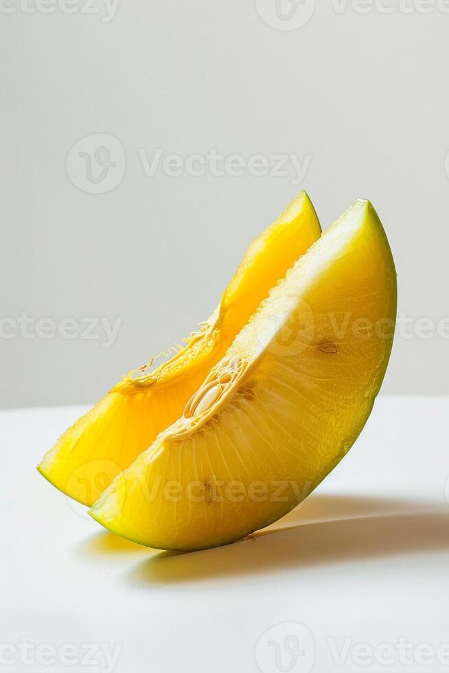 A cut up yellow melon on a white surface photo
