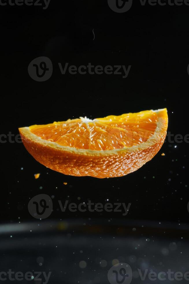 A slice of orange is falling into a bowl of water photo