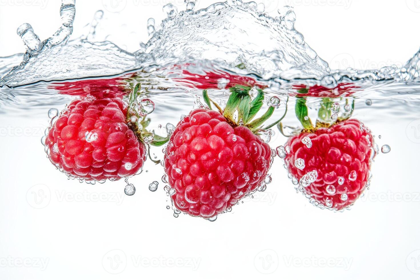 Three raspberries are splashing into the water photo