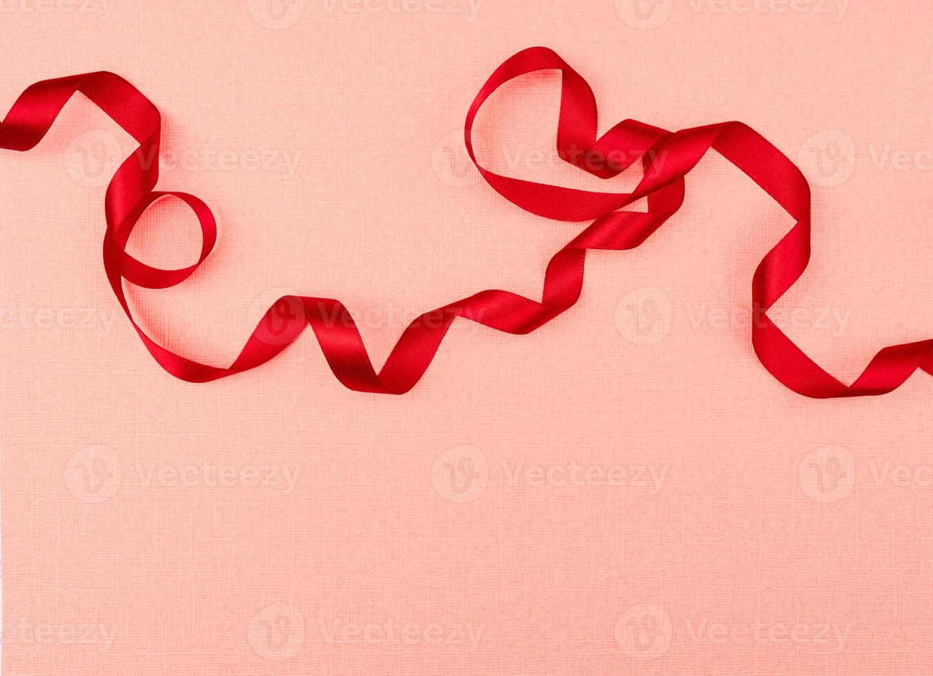 Red wavy ribbon on pink background. Holiday decoration. Valentine's Day decoration congratulation frame. photo