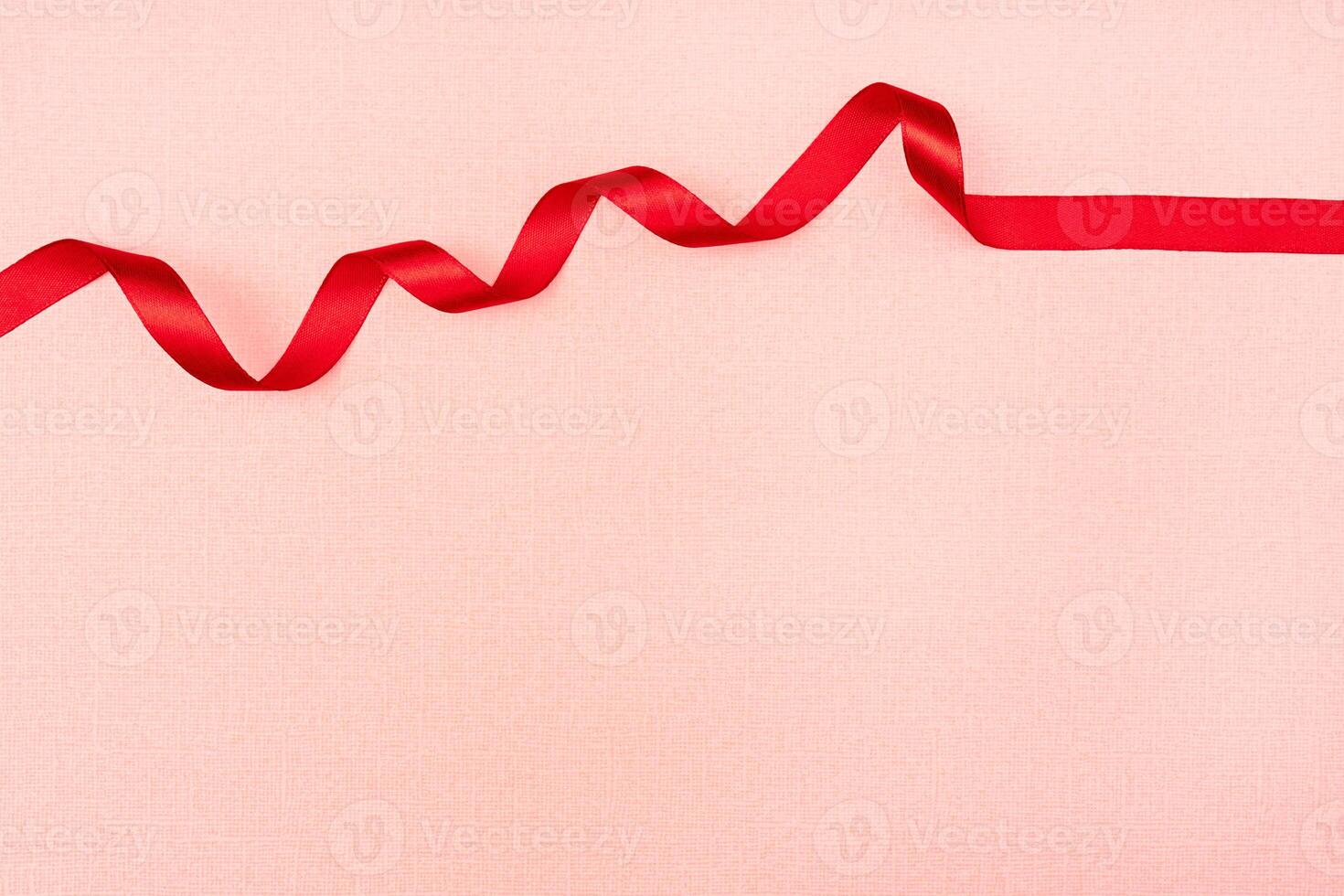 Red wavy ribbon on pink background. Holiday decoration. Valentine's Day decoration congratulation frame. photo