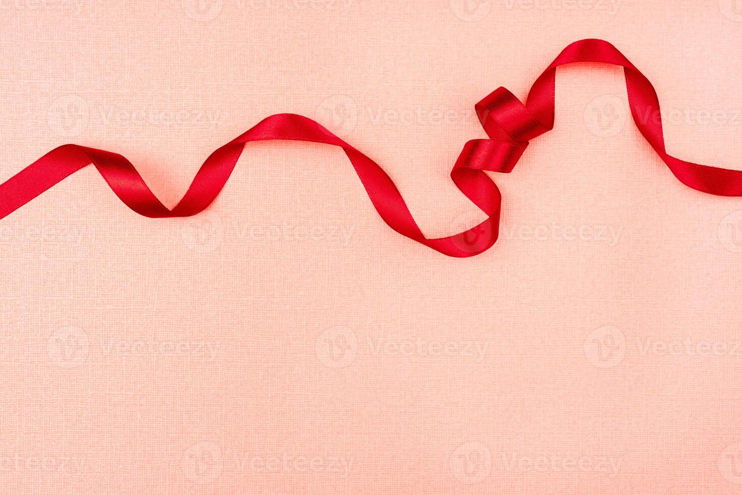 Red wavy ribbon on pink background. Holiday decoration. Valentine's Day decoration congratulation frame. photo