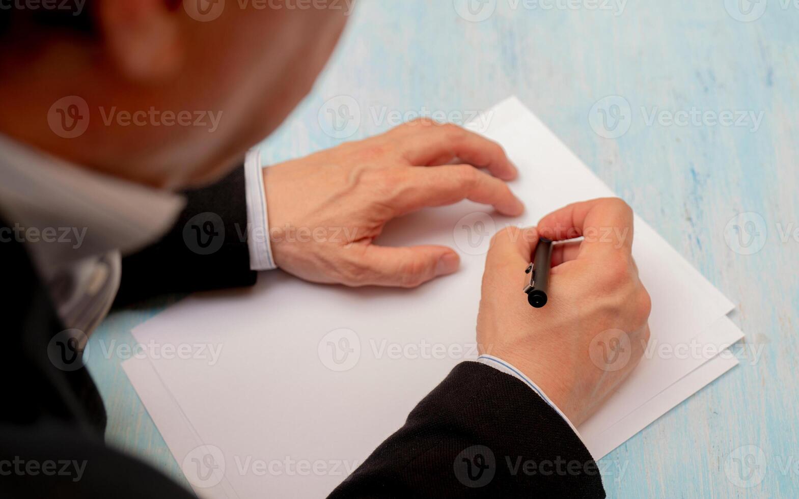 A pen in a man's hand. White sheet of paper. Signing a document. photo