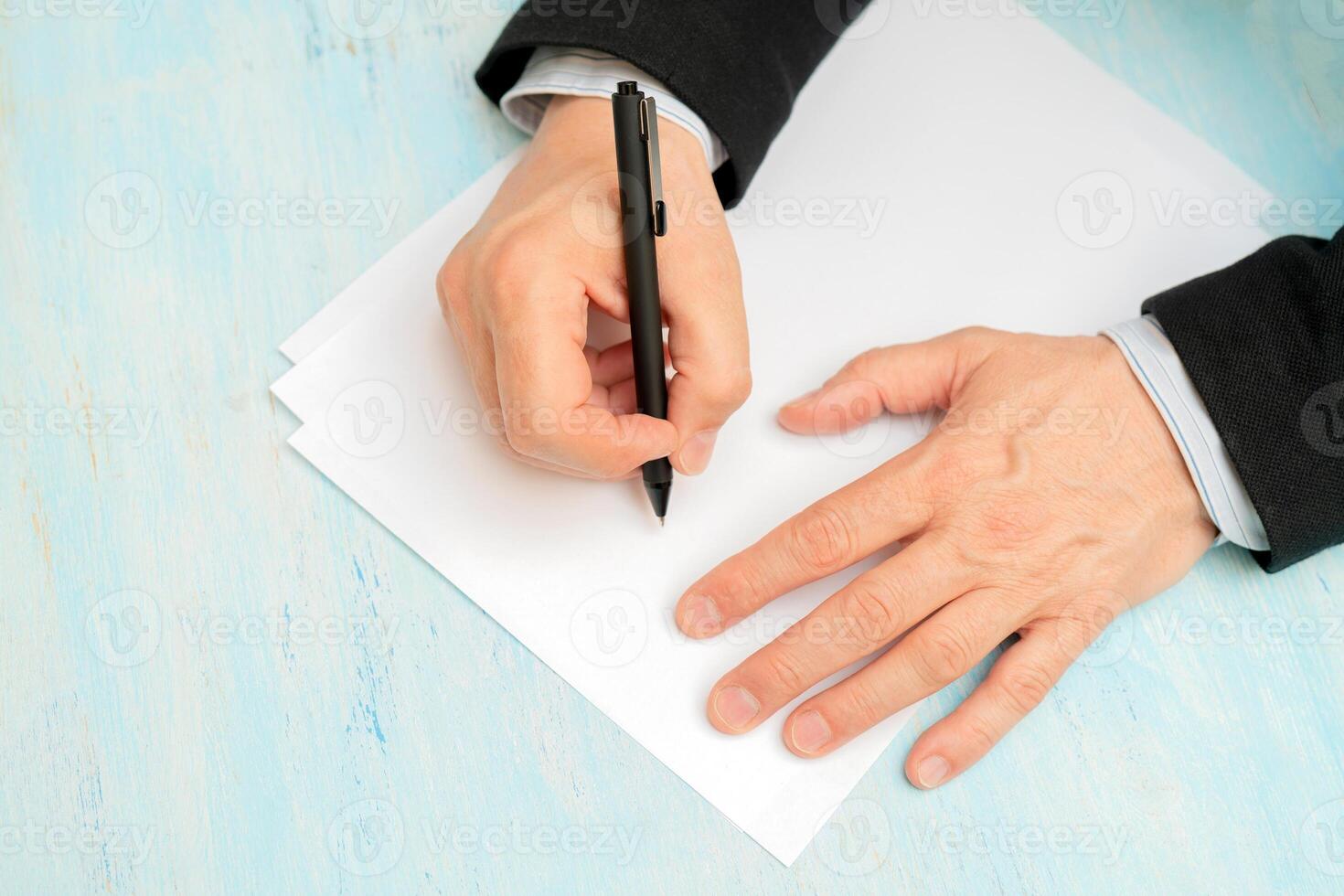 A pen in a man's hand. White sheet of paper. Signing a document. photo