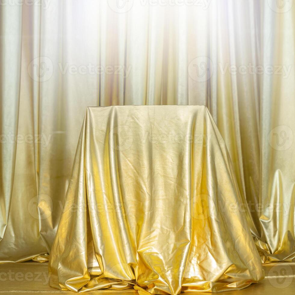Stand draped in gold fabric. Abstract golden background. photo