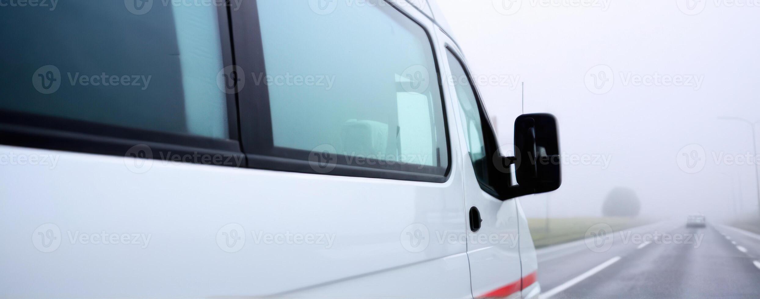 A white van is driving down the road in the fog photo