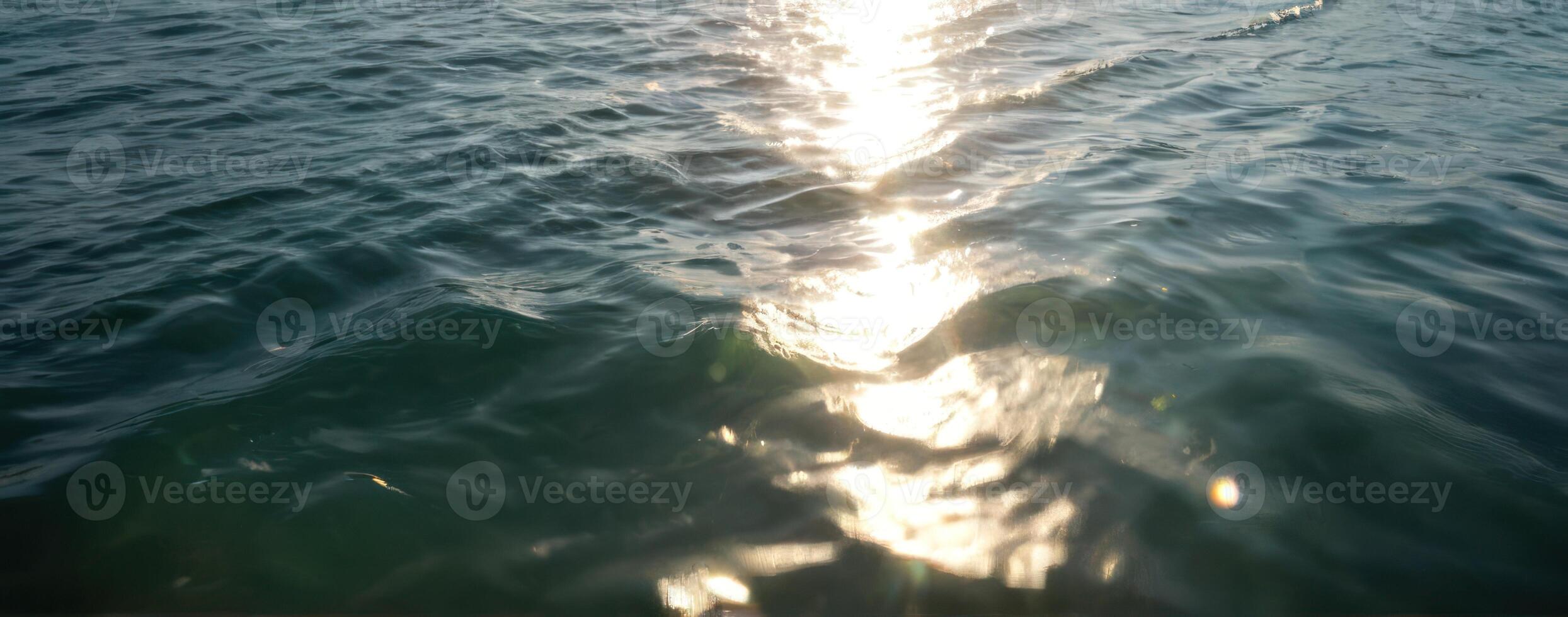 The sun shines through the water on a boat photo