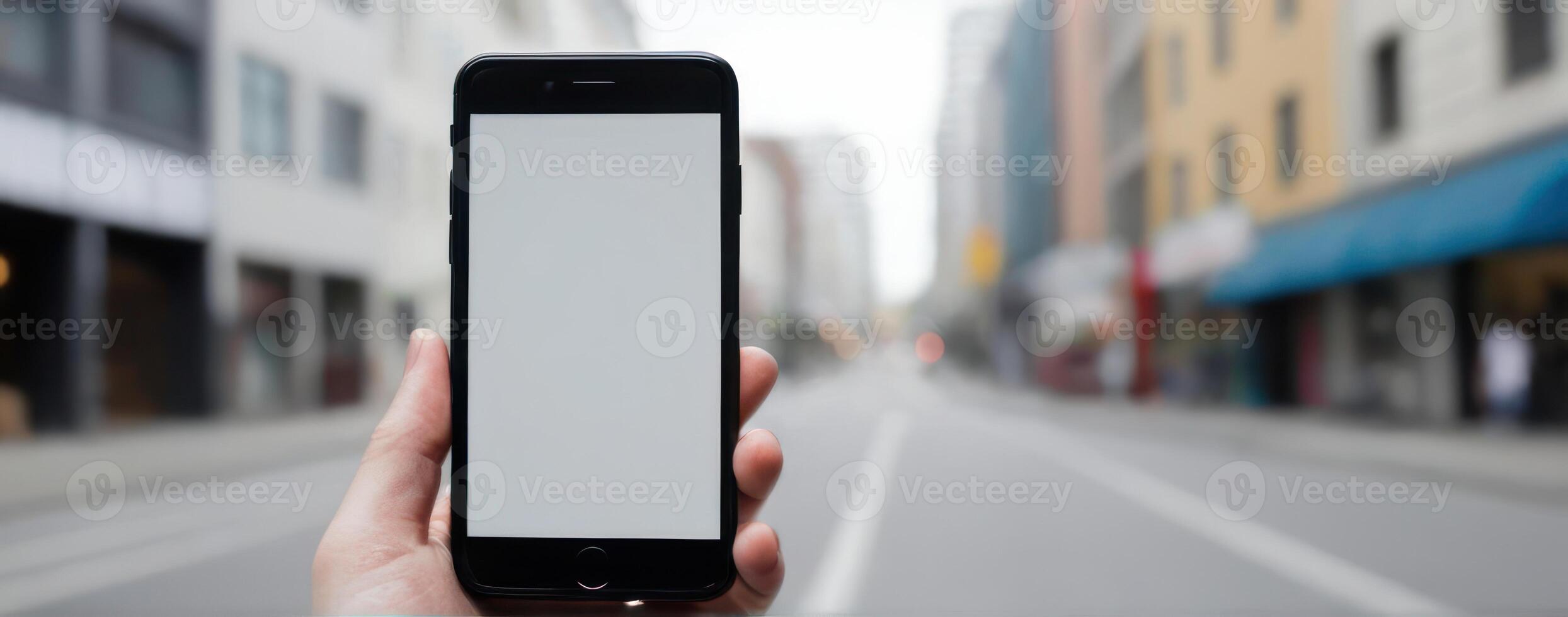 A person holding an iphone in front of an empty street photo