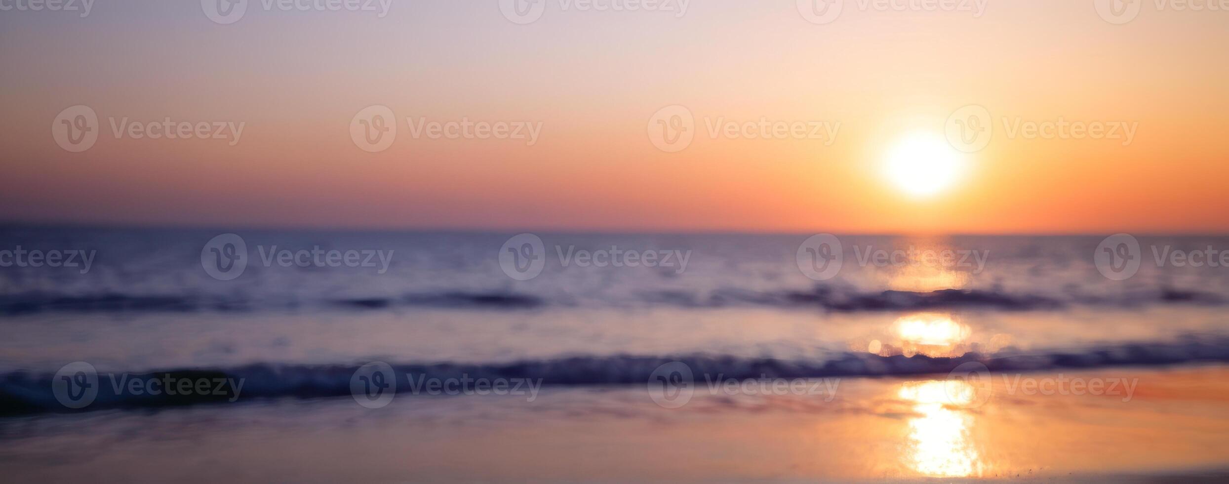 A blurry image of the sun setting over the ocean photo