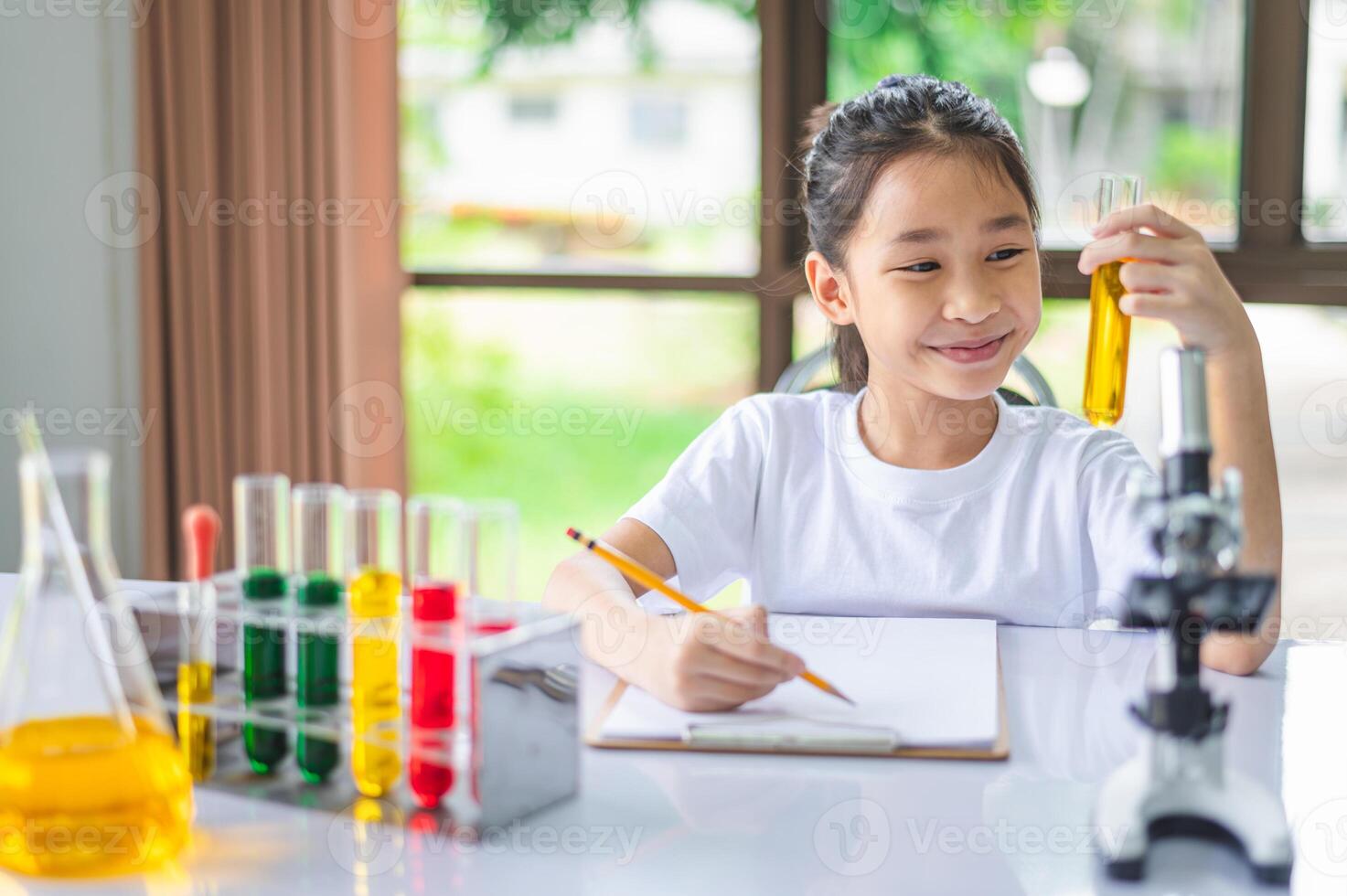little scientist looking through a microscope and test tubes filled with chemicals for learning about science and experiments. photo