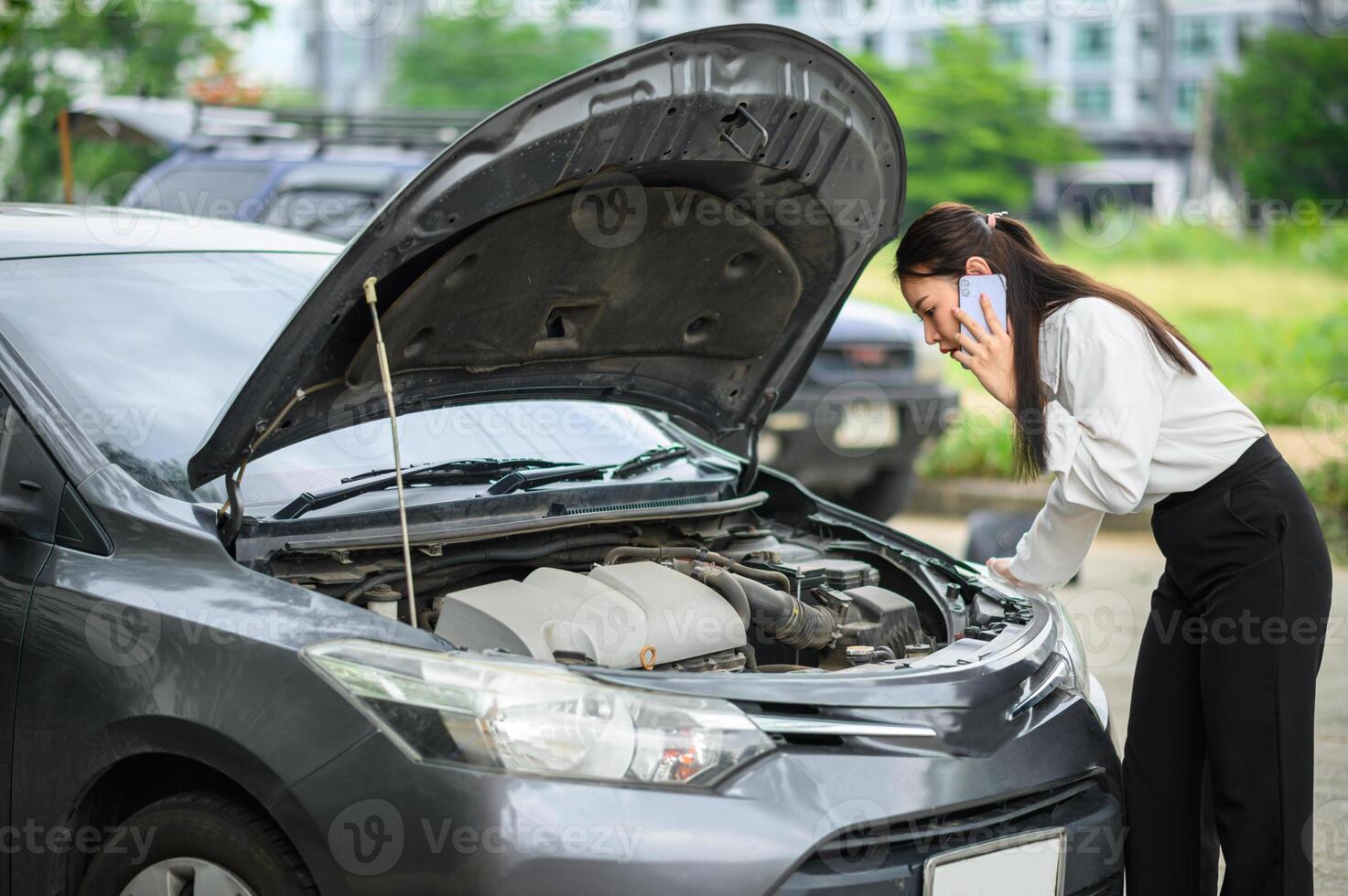 female motorist is calling an insurance or recovery service officer for assistance related to a car accident. photo