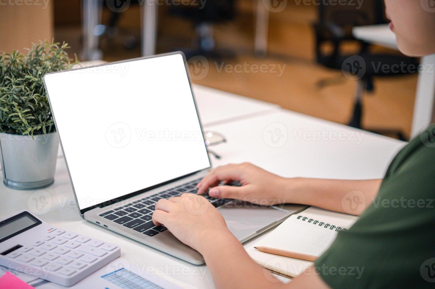 Mockup image of a woman's hand working on a laptop with blank white desktop copy space screen on a desk photo