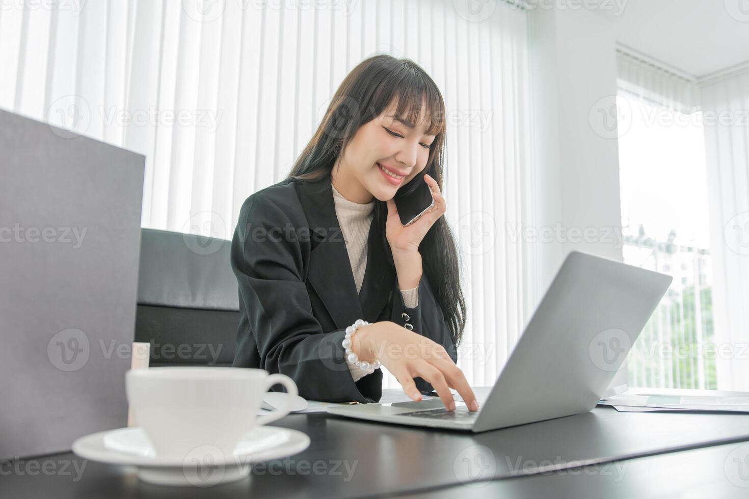 woman talking on the mobile phone and smiling while sitting at her working place in office. photo