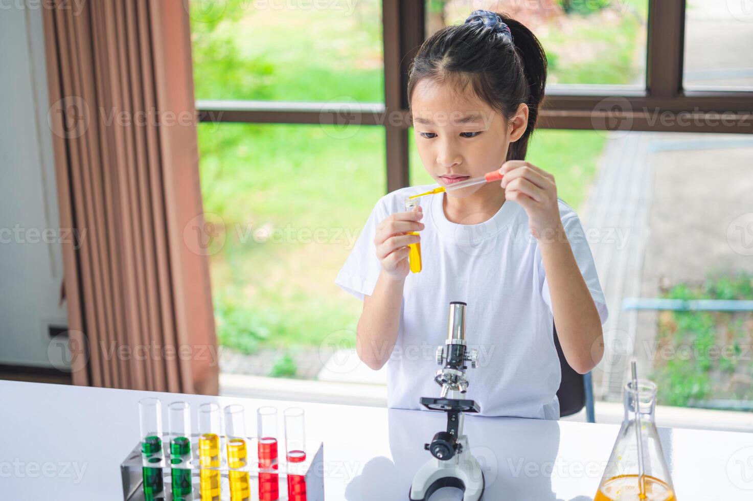 little scientist looking through a microscope and test tubes filled with chemicals for learning about science and experiments. photo