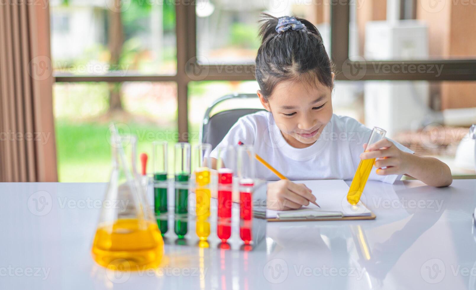 little scientist looking through a microscope and test tubes filled with chemicals for learning about science and experiments. photo