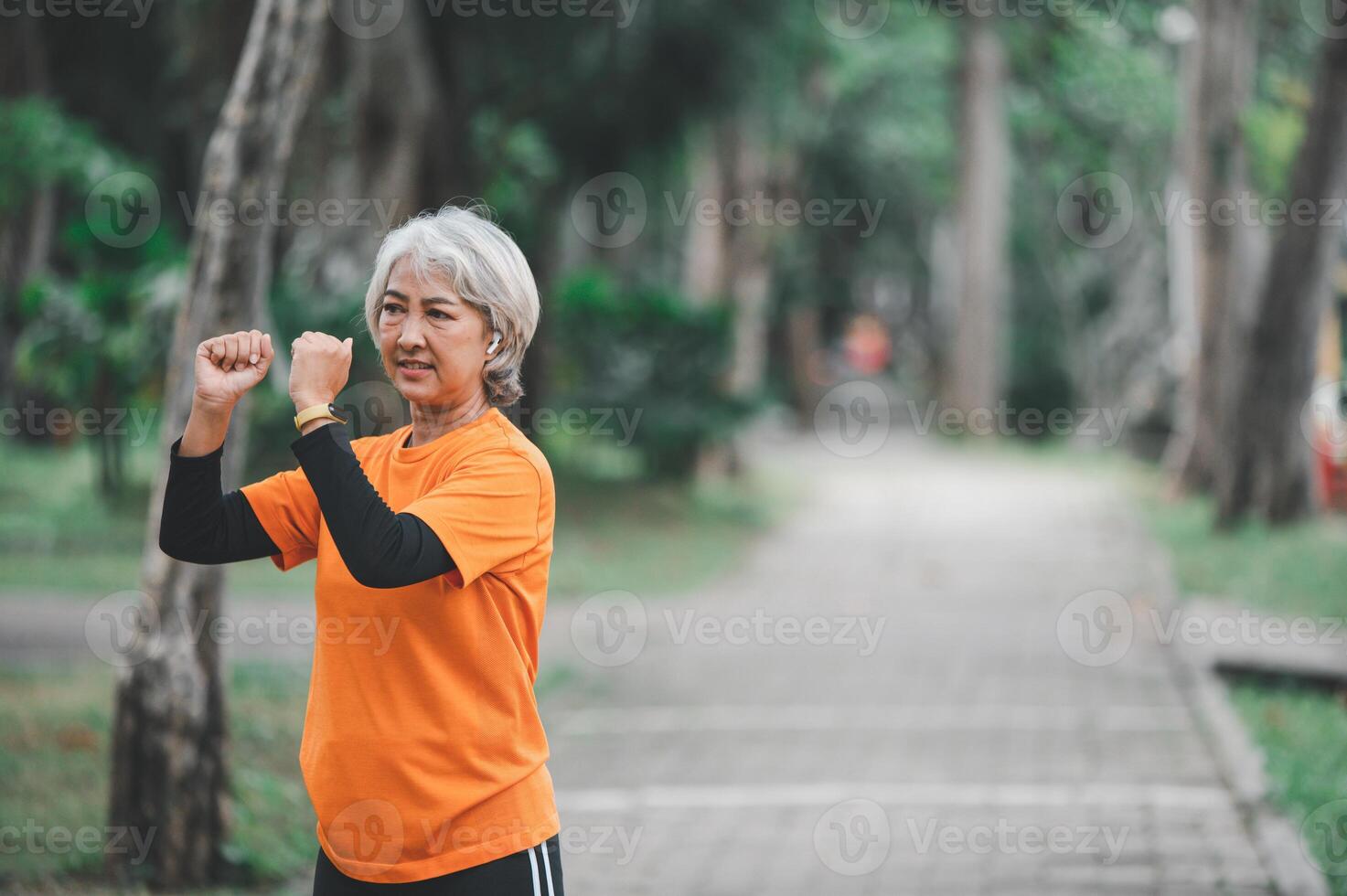 white-haired elderly person exercising in the park early in the morning. photo