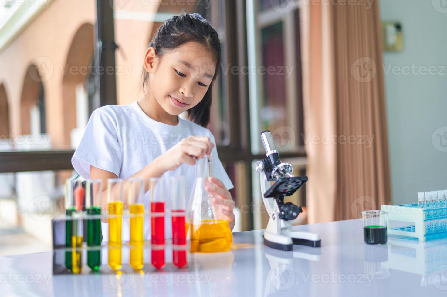 little scientist looking through a microscope and test tubes filled with chemicals for learning about science and experiments. photo