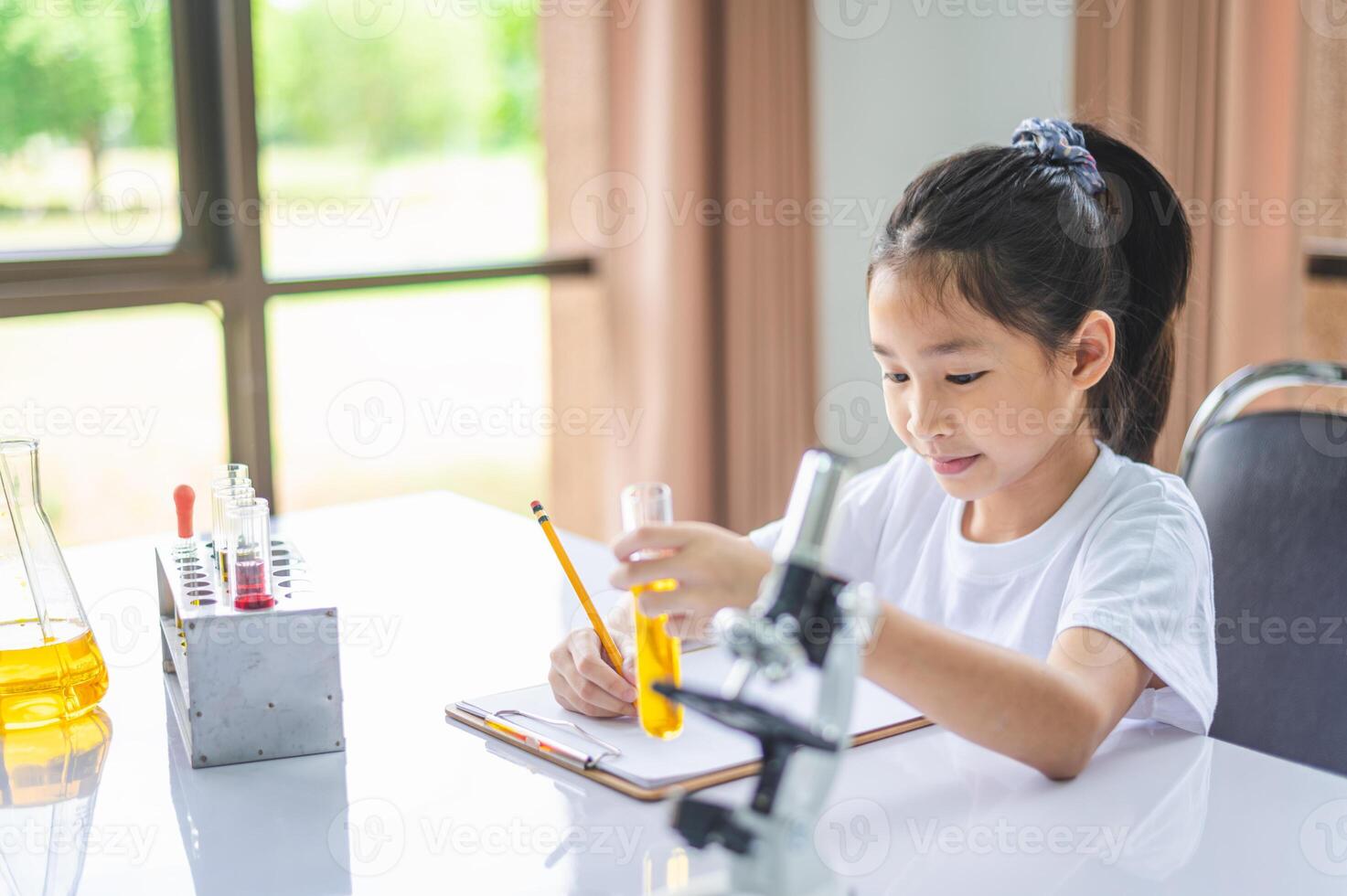little scientist looking through a microscope and test tubes filled with chemicals for learning about science and experiments. photo