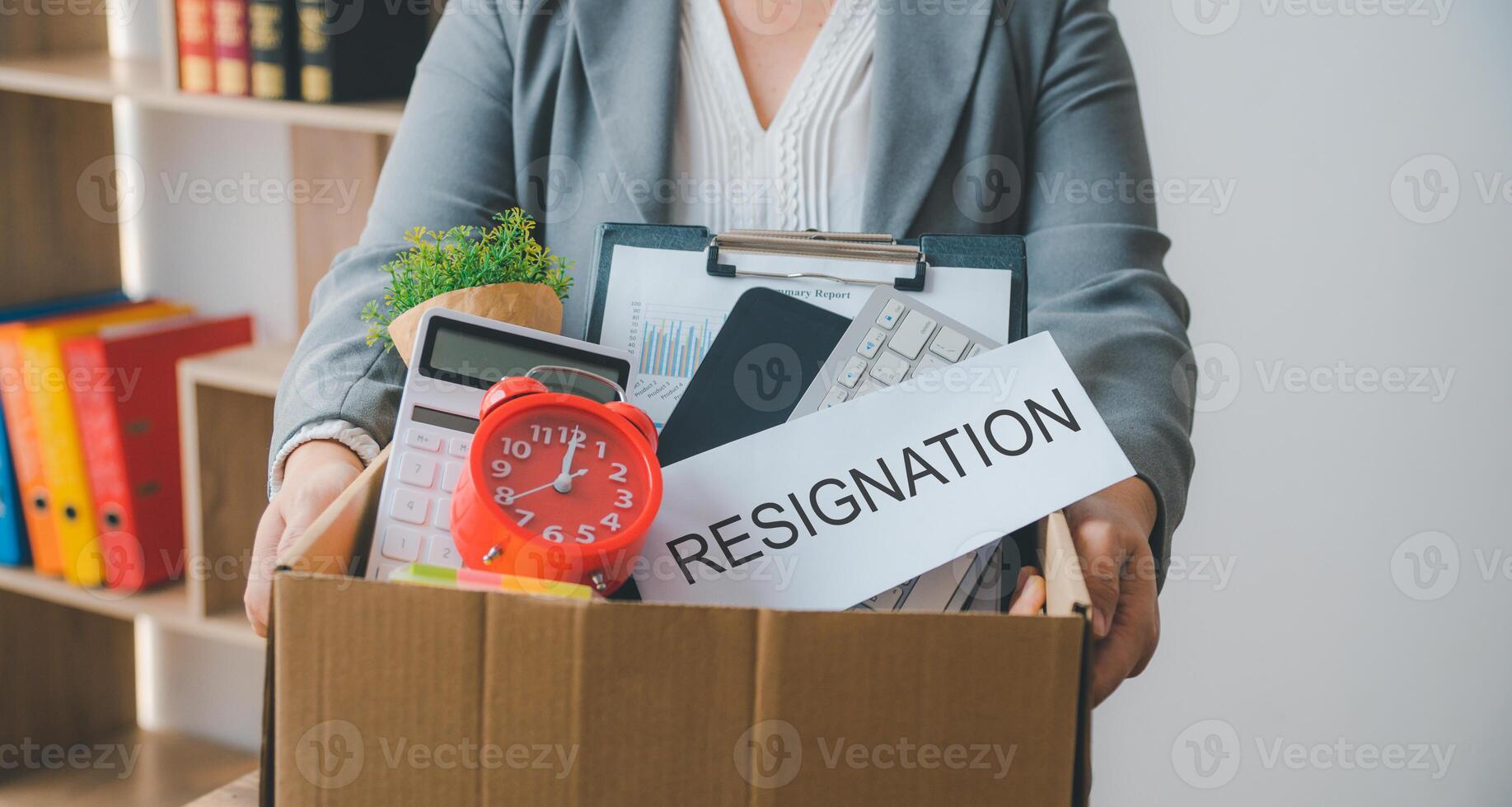 Female firm employee leaving the office with cardboard boxes containing office supplies and personal items after quitting to find a new job, being fired, or being fired from the company. photo