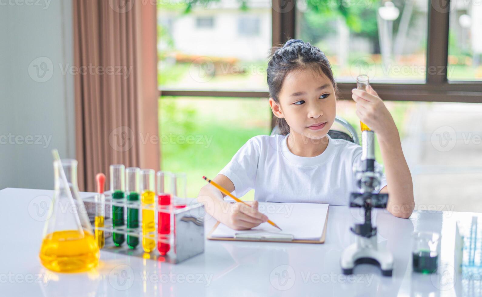 little scientist looking through a microscope and test tubes filled with chemicals for learning about science and experiments. photo