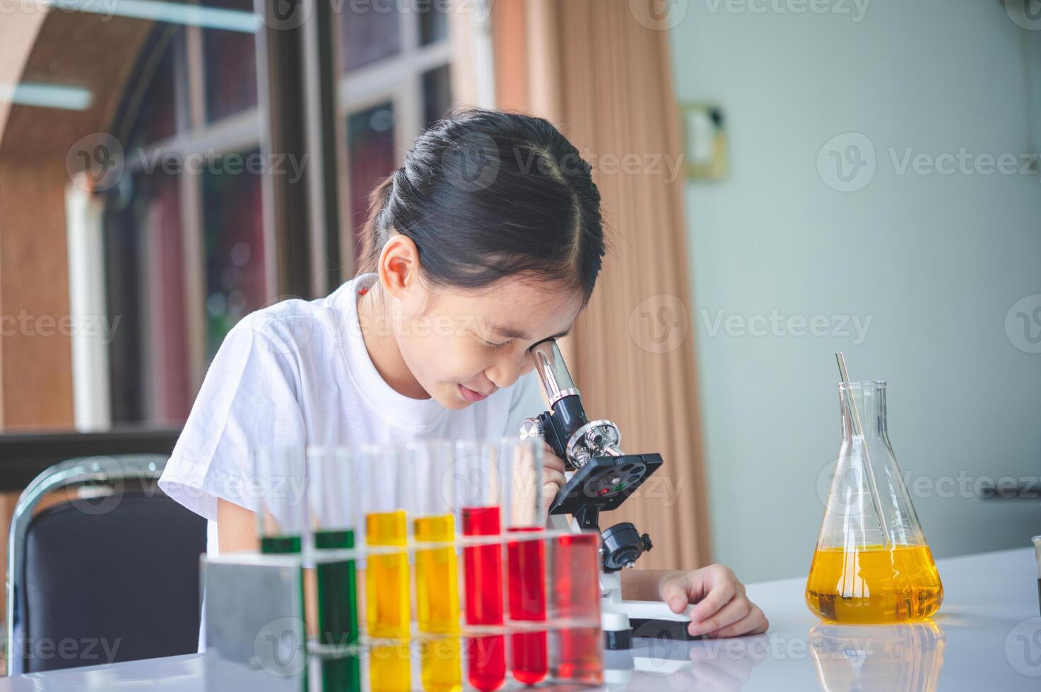little scientist looking through a microscope and test tubes filled with chemicals for learning about science and experiments. photo