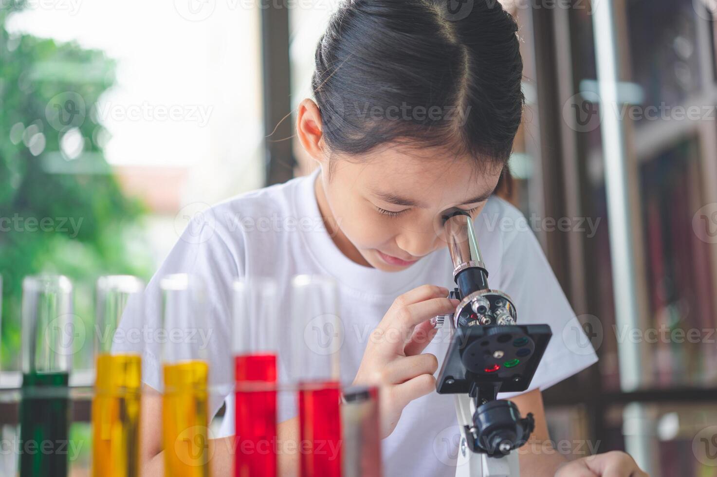little scientist looking through a microscope and test tubes filled with chemicals for learning about science and experiments. photo