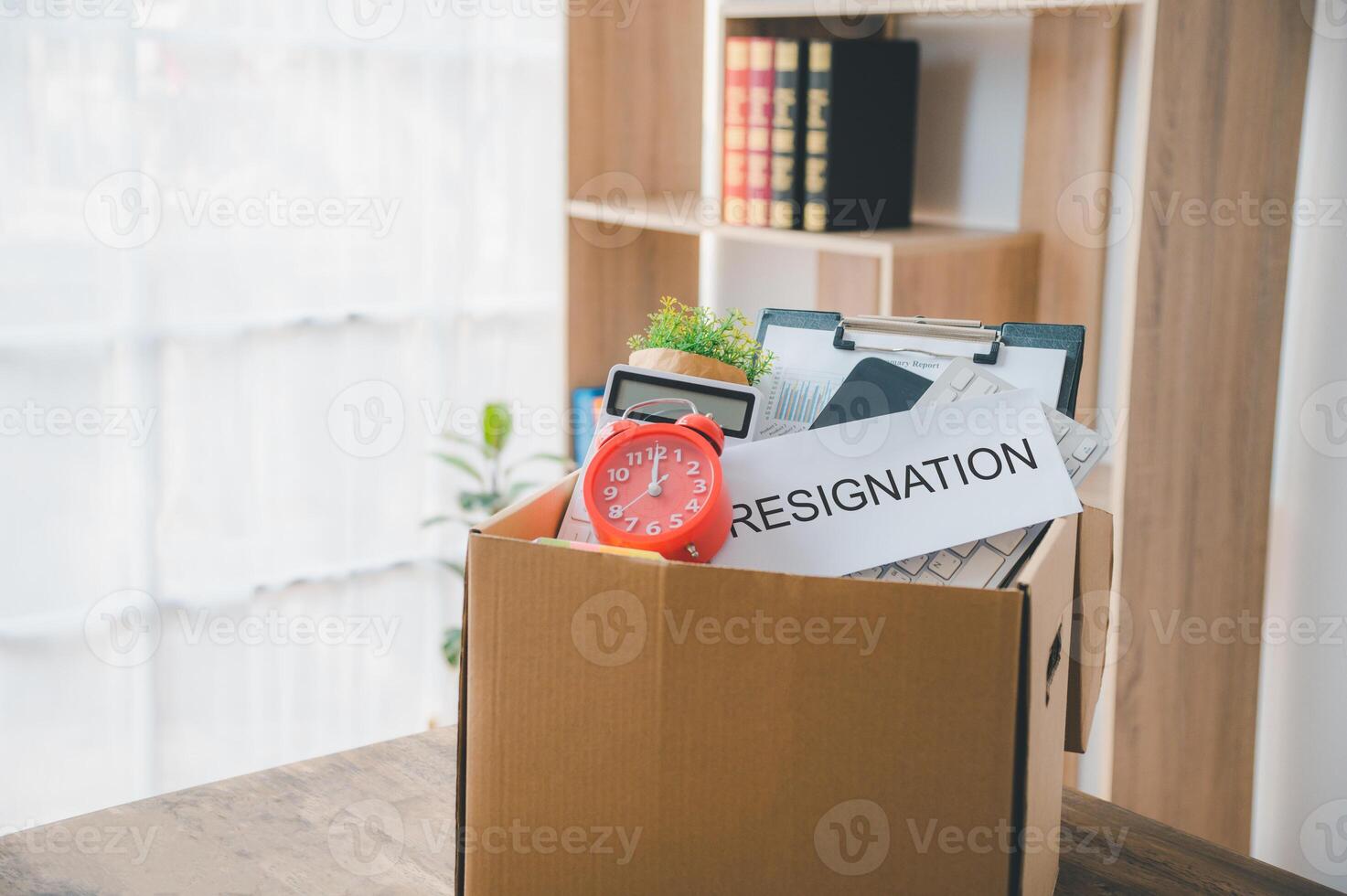 On the desk is a cardboard box containing office supplies. Resignation, dismissal, switching jobs, or getting fired from a corporation. photo