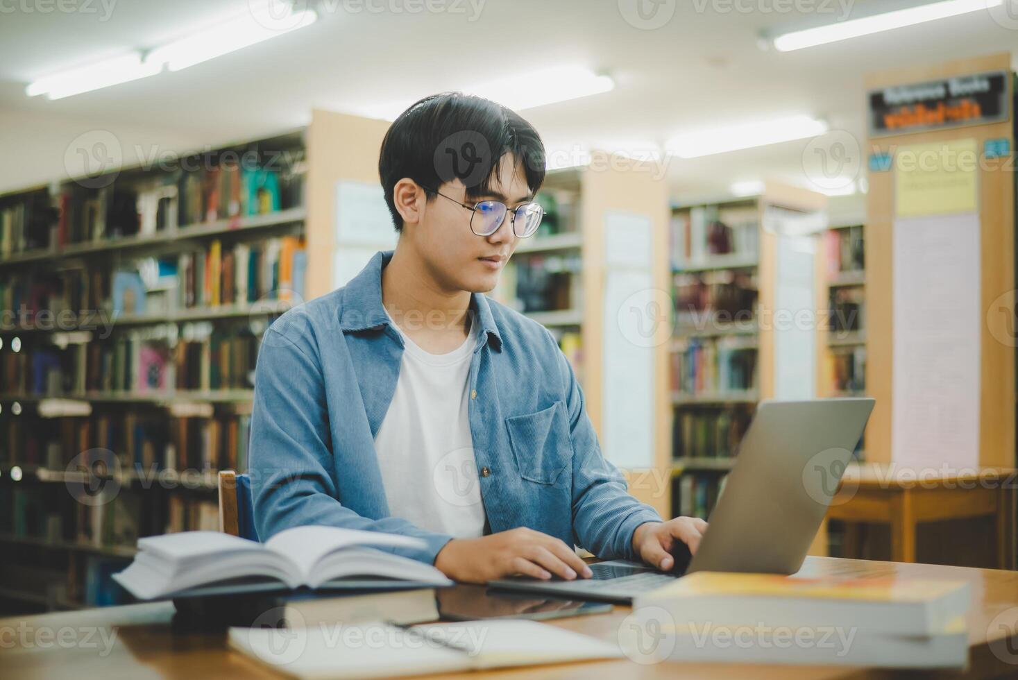 masculino Universidad estudiantes son trabajando en laptops y buscando para libros a estudiar, hacer informes, encontrar útil información en Universidad habitación. concepto de lectura, aprendizaje y inteligencia. foto