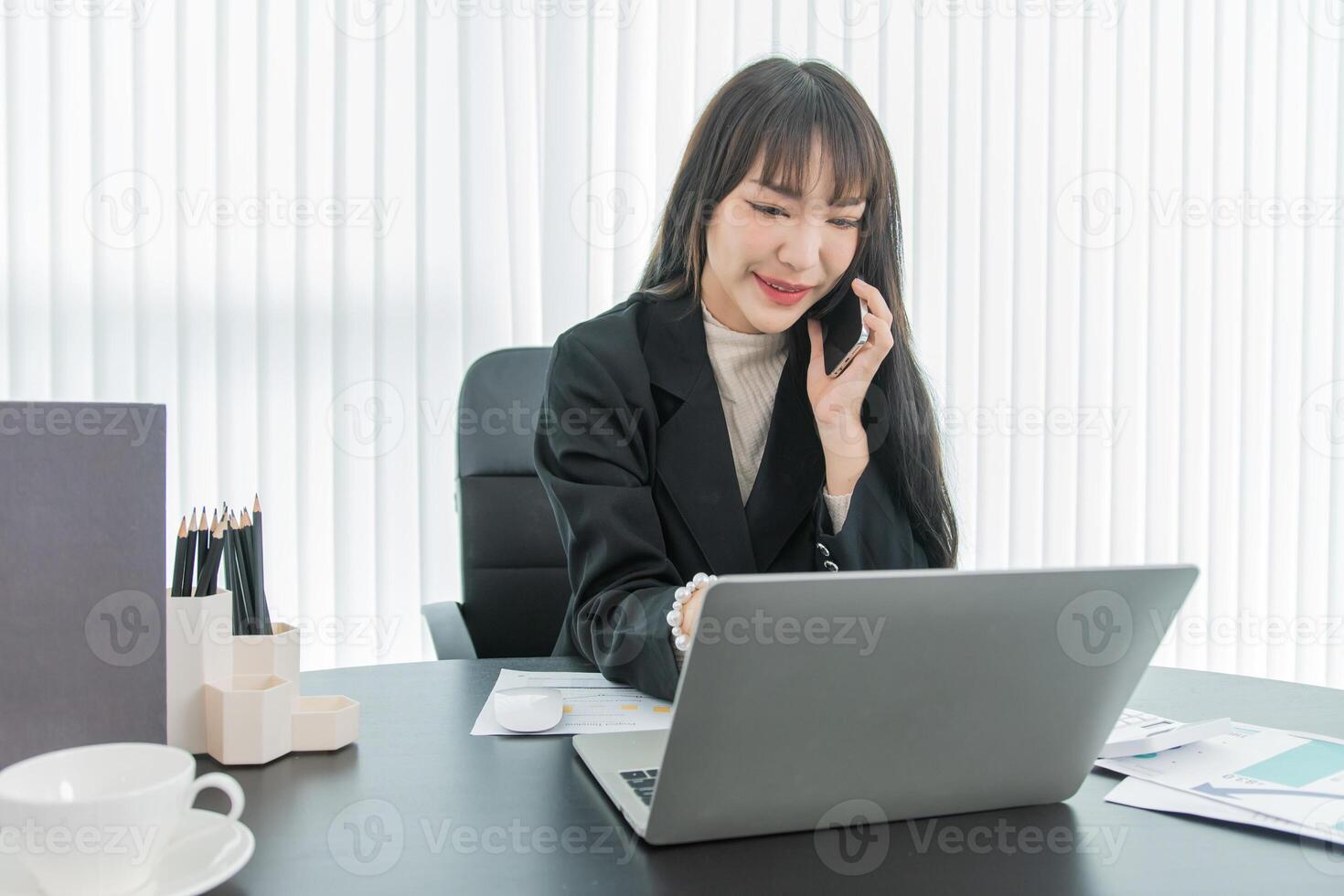 woman talking on the mobile phone and smiling while sitting at her working place in office. photo
