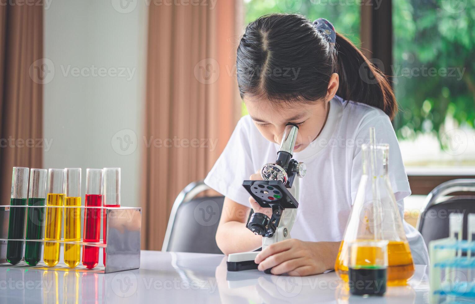 little scientist looking through a microscope and test tubes filled with chemicals for learning about science and experiments. photo