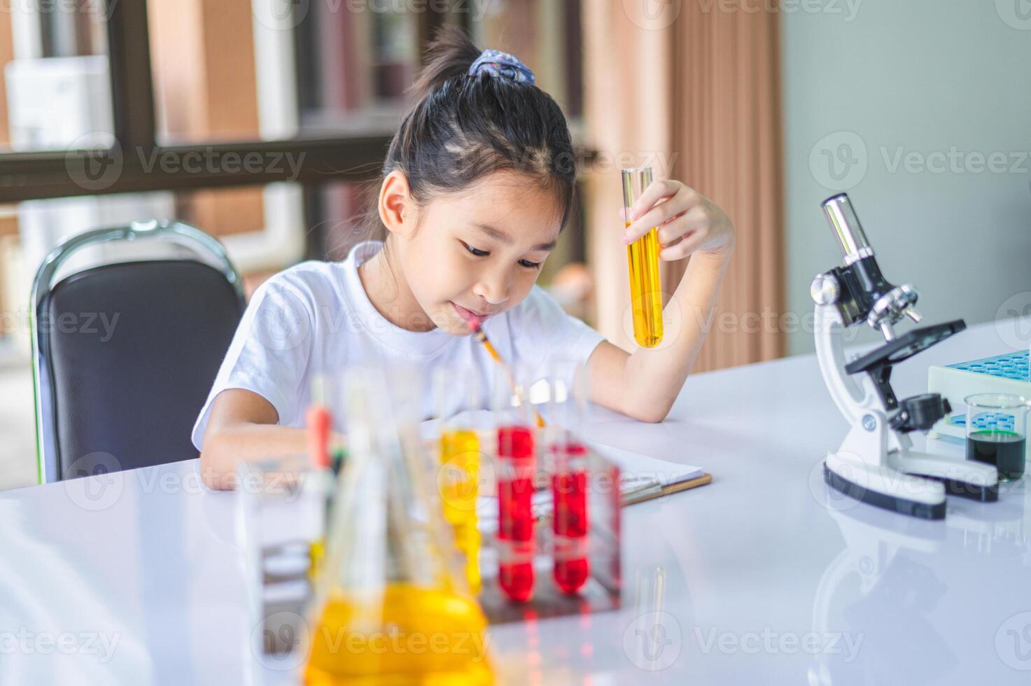 little scientist looking through a microscope and test tubes filled with chemicals for learning about science and experiments. photo
