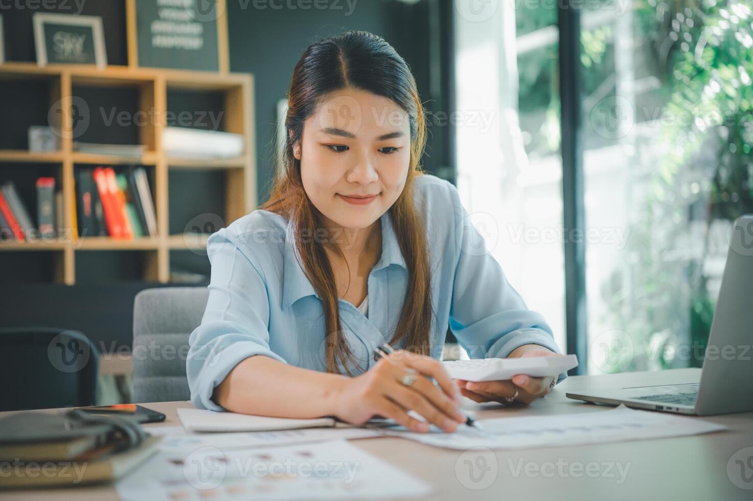Business asian woman sitting at a desk at an office By using the calculator to work. Business Concept Analysis and Planning photo