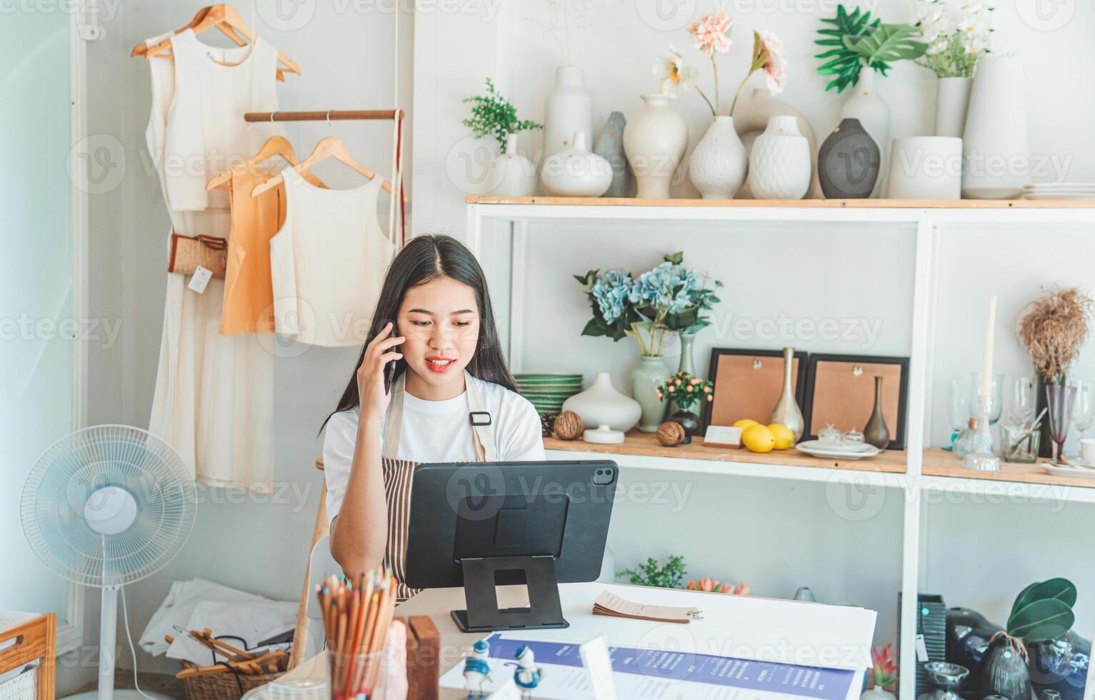 Small business owner talking on the phone with customers in a small shop. and check orders, check the orders that customers order from online retailers - online shopping photo