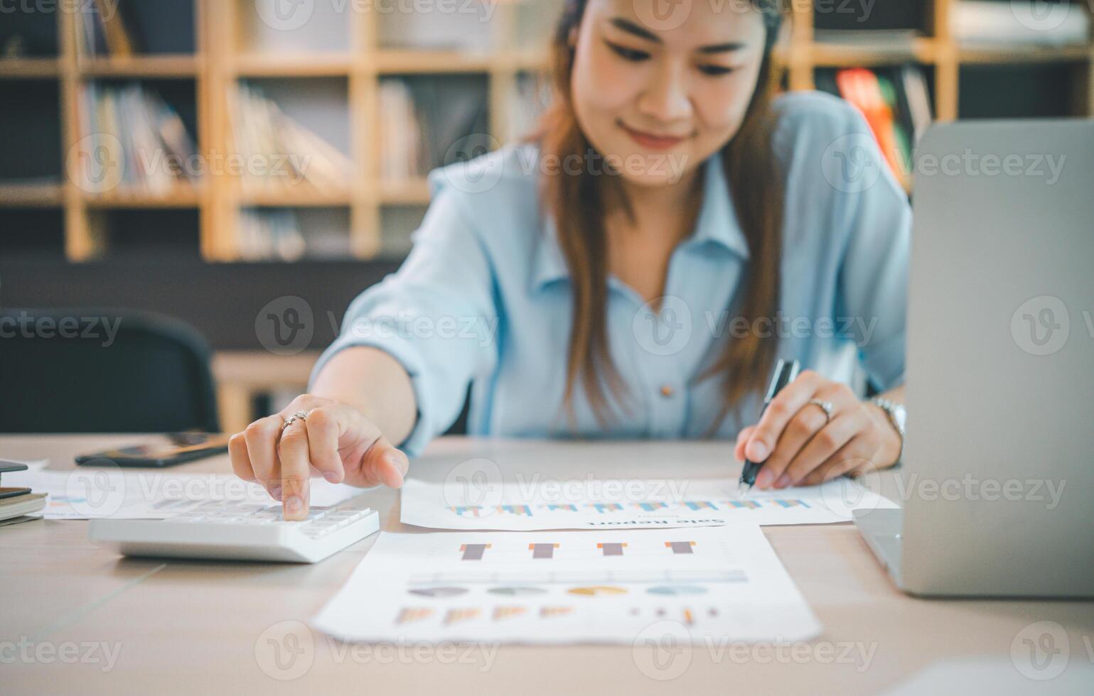 Business asian woman sitting at a desk at an office By using the calculator to work. Business Concept Analysis and Planning photo
