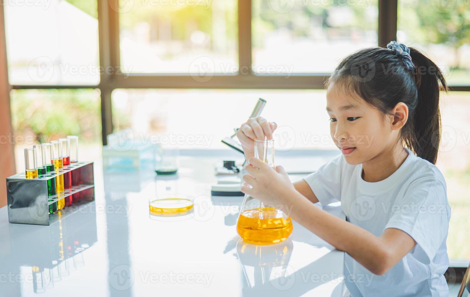little scientist looking through a microscope and test tubes filled with chemicals for learning about science and experiments. photo