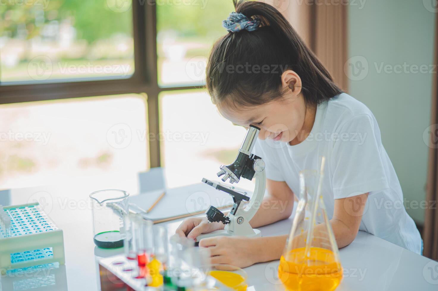 little scientist looking through a microscope and test tubes filled with chemicals for learning about science and experiments. photo