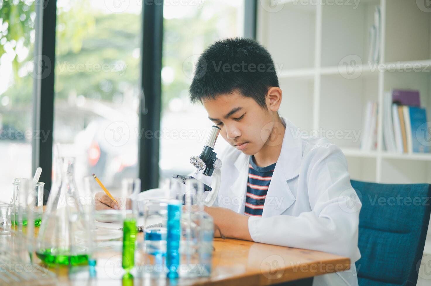 Asian male science students looking through a microscope and tests of plants in the classroom. Learning about scientific experiments on plant species. photo