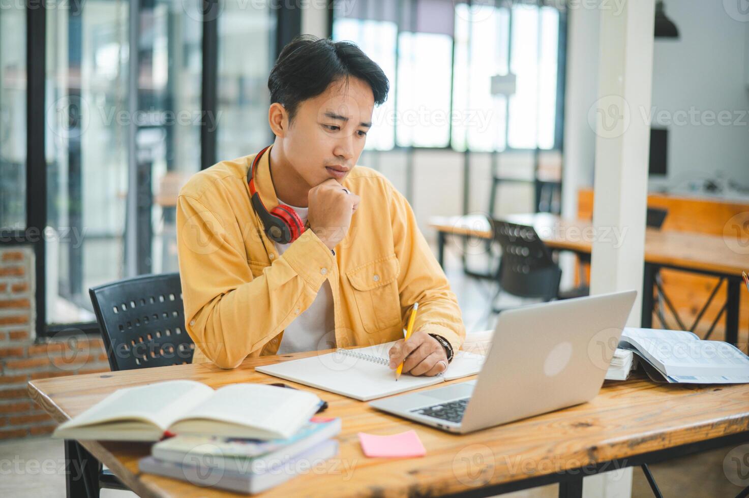 Young Asian college student working and learning on laptop In the cafe. Searching for knowledge online. photo