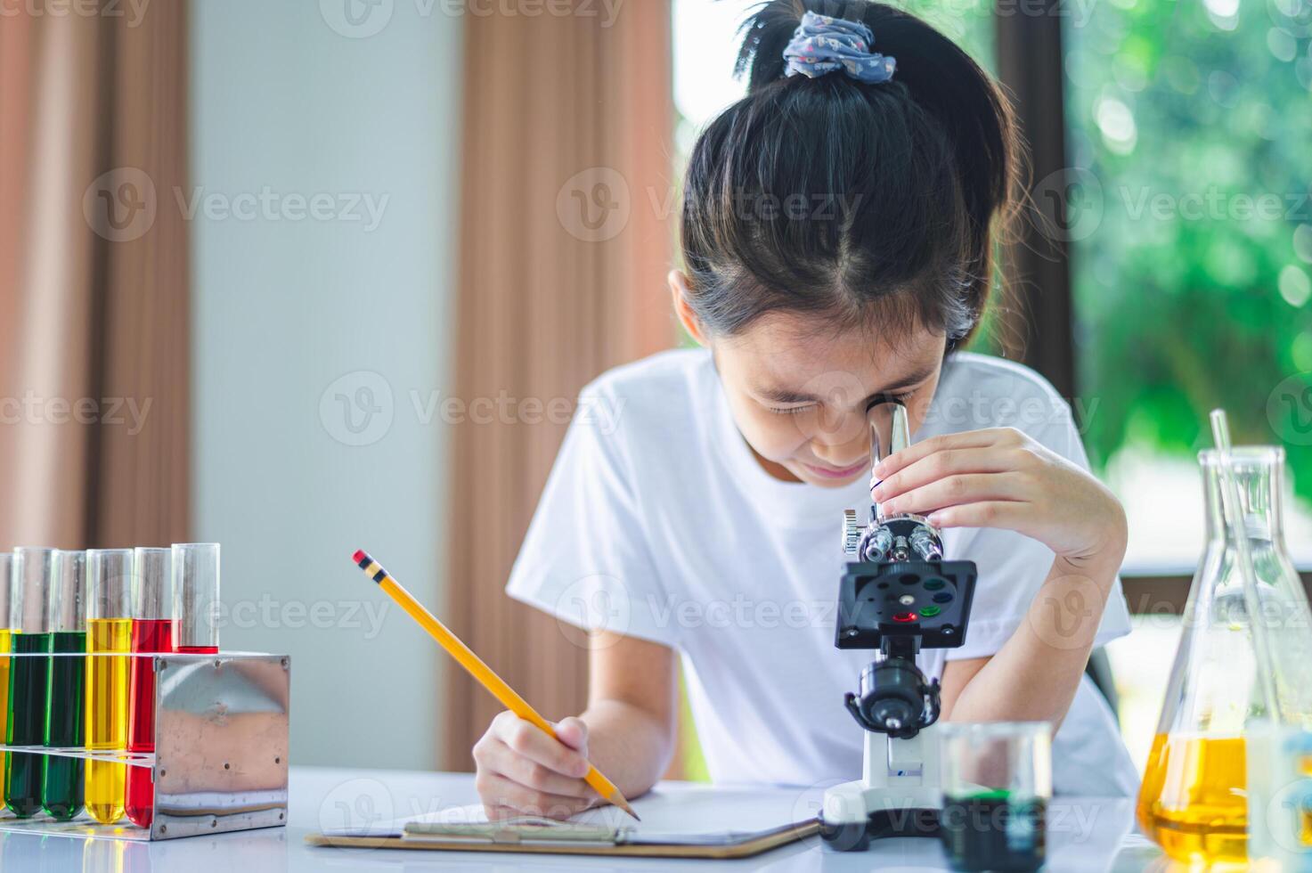 little scientist looking through a microscope and test tubes filled with chemicals for learning about science and experiments. photo