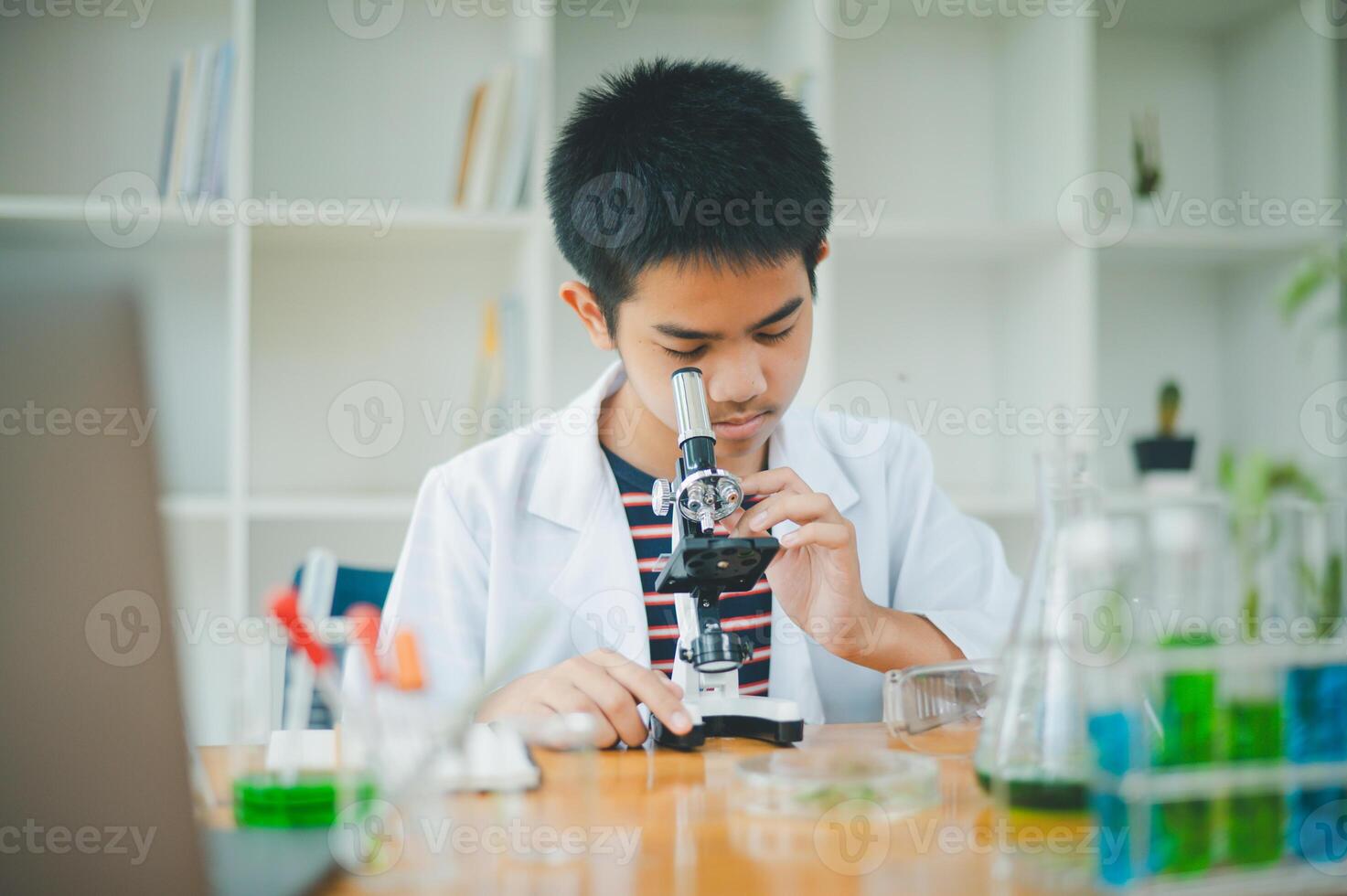 Asian male science students looking through a microscope and tests of plants in the classroom. Learning about scientific experiments on plant species. photo