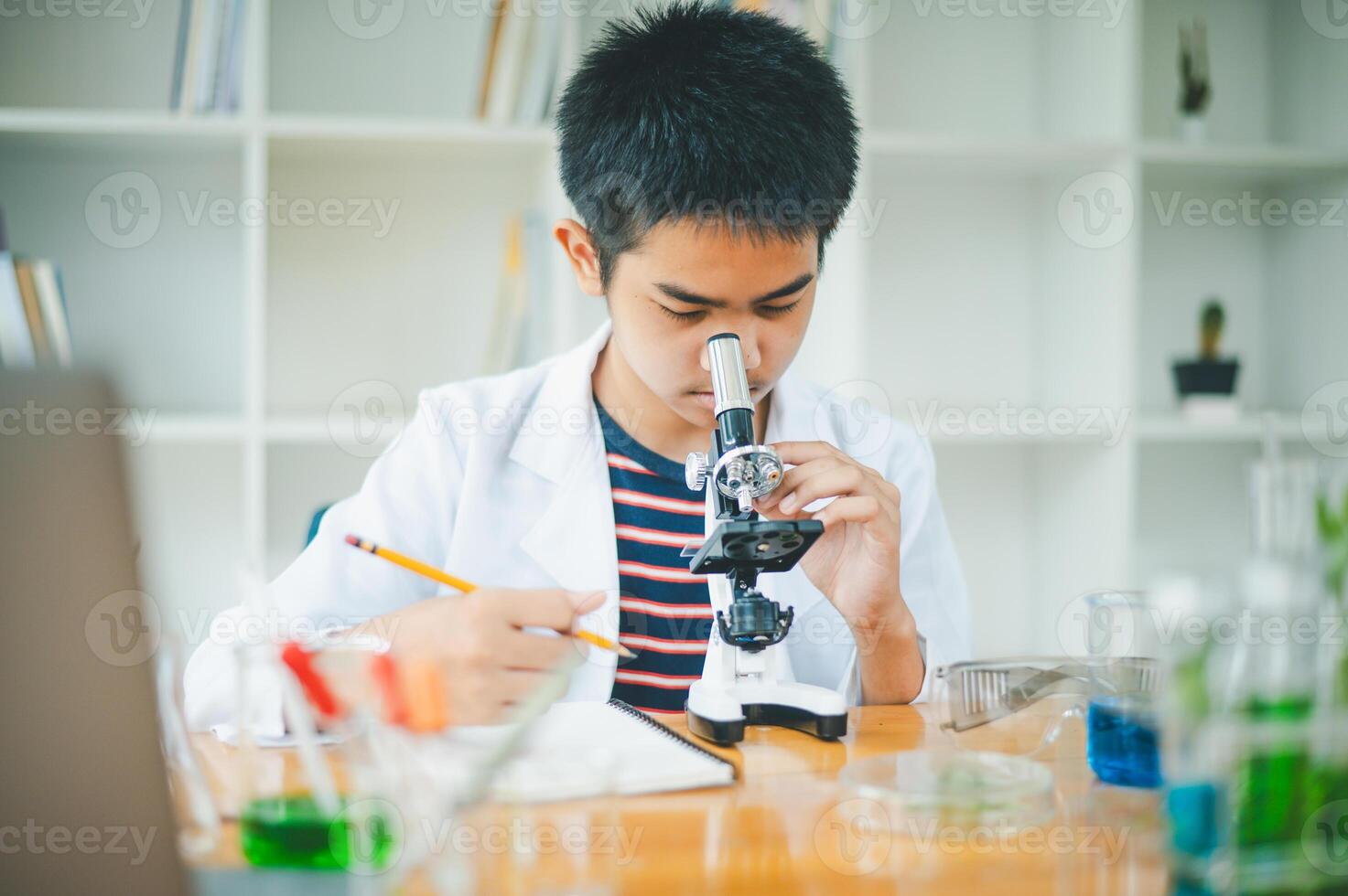 Asian male science students looking through a microscope and tests of plants in the classroom. Learning about scientific experiments on plant species. photo