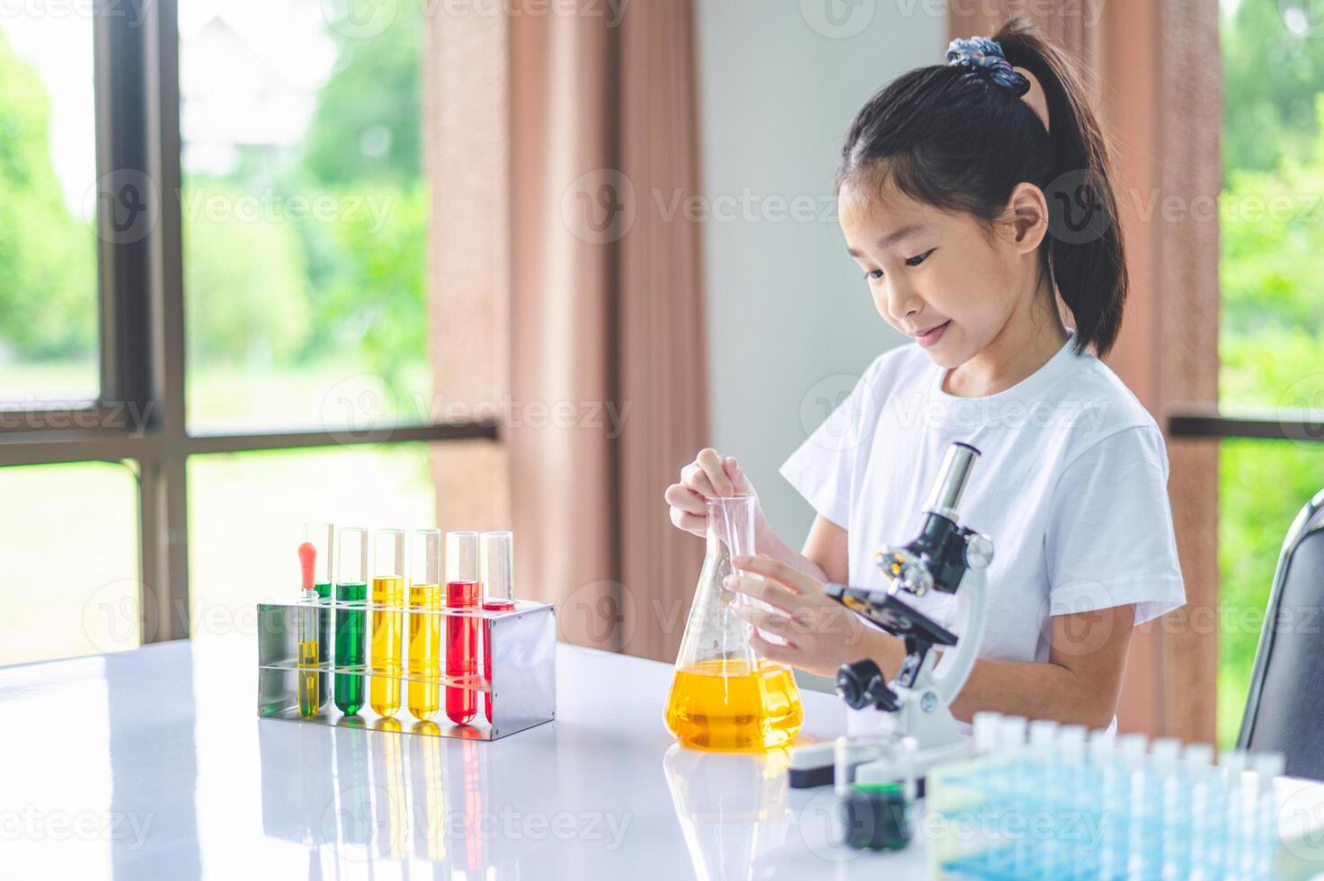little scientist looking through a microscope and test tubes filled with chemicals for learning about science and experiments. photo
