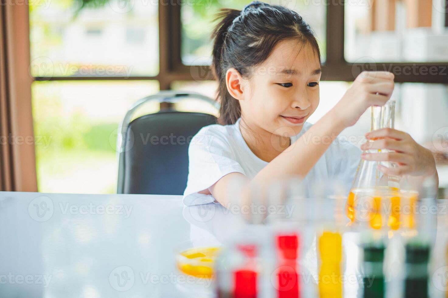 little scientist looking through a microscope and test tubes filled with chemicals for learning about science and experiments. photo