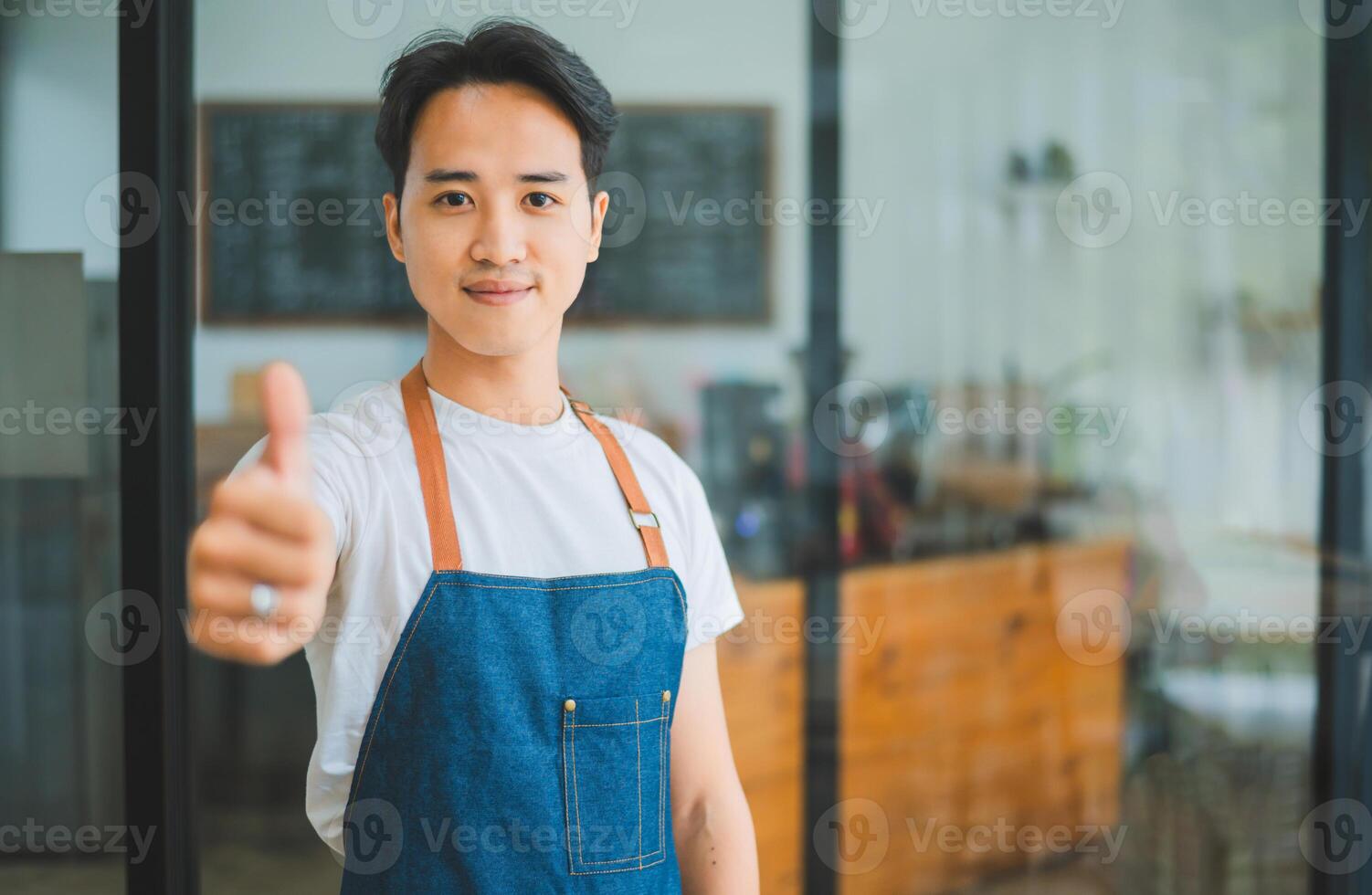 Smiling Asian coffee shop owner standing in front of cashier counter.welcome customers who come in to place orders in the cafe. photo